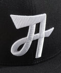 Limited first edition 'A' cap, a classic snapback by Uppr Lowr. The cap features a hand-drawn custom letterform 'A' by Travis Price, exclusive for Uppr Lowr. Crafted from a wool blend, it showcases custom raised embroidery and a deep fit. This collectable cap is a must-have for streetwear enthusiasts.