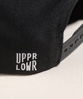Limited first edition 'A' cap, a classic snapback by Uppr Lowr. The cap features a hand-drawn custom letterform 'A' by Travis Price, exclusive for Uppr Lowr. Crafted from a wool blend, it showcases custom raised embroidery and a deep fit. This collectable cap is a must-have for streetwear enthusiasts.